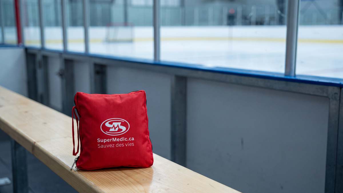 Trousse de premiers soins SuperMedic rouge posée sur un banc de joueurs dans un aréna de hockey