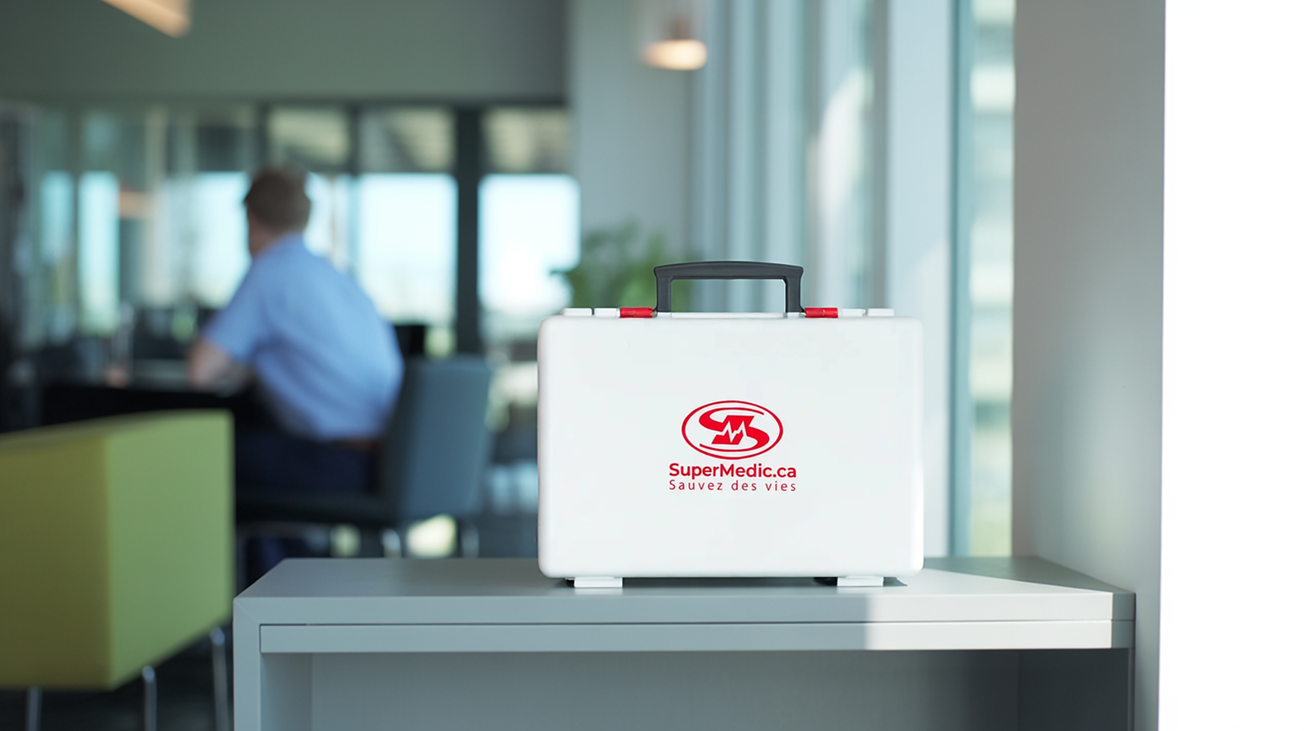 Mallette de premiers soins SuperMedic blanche sur une tablette dans un bureau moderne